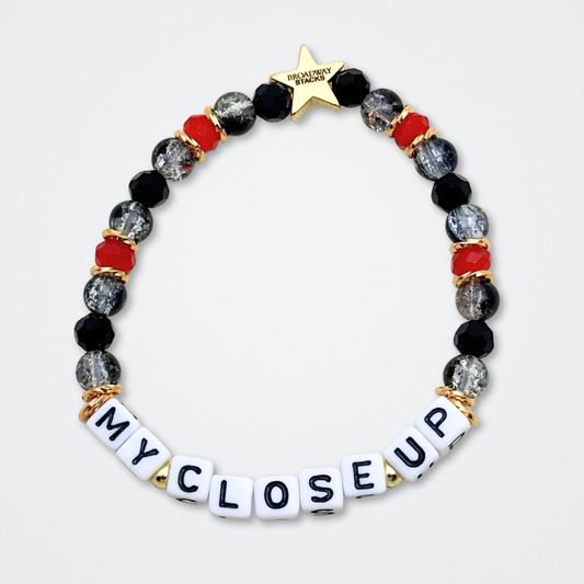 Broadway Stacks CLOSE-UP Collection. 6 stretch bracelets included in Stack. Red, black and gold colored beads. Letter beads that spell quotes. Gold star logo bead to remind you that you shine. Sunset Blvd fans. 
