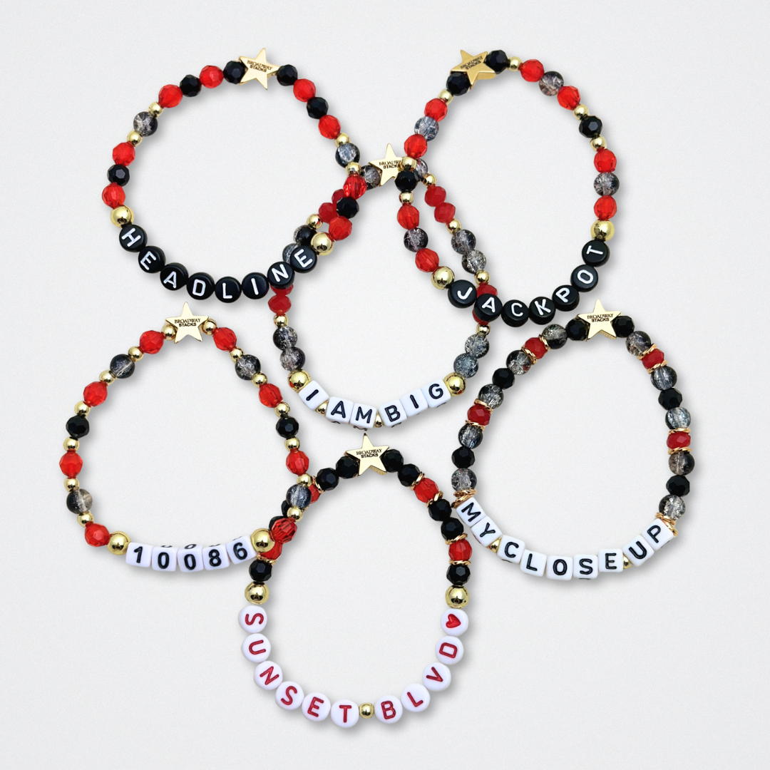 Broadway Stacks CLOSE-UP Collection. 6 stretch bracelets included in Stack. Red, black and gold colored beads. Letter beads that spell quotes. Gold star logo bead to remind you that you shine. Sunset Blvd fans. 