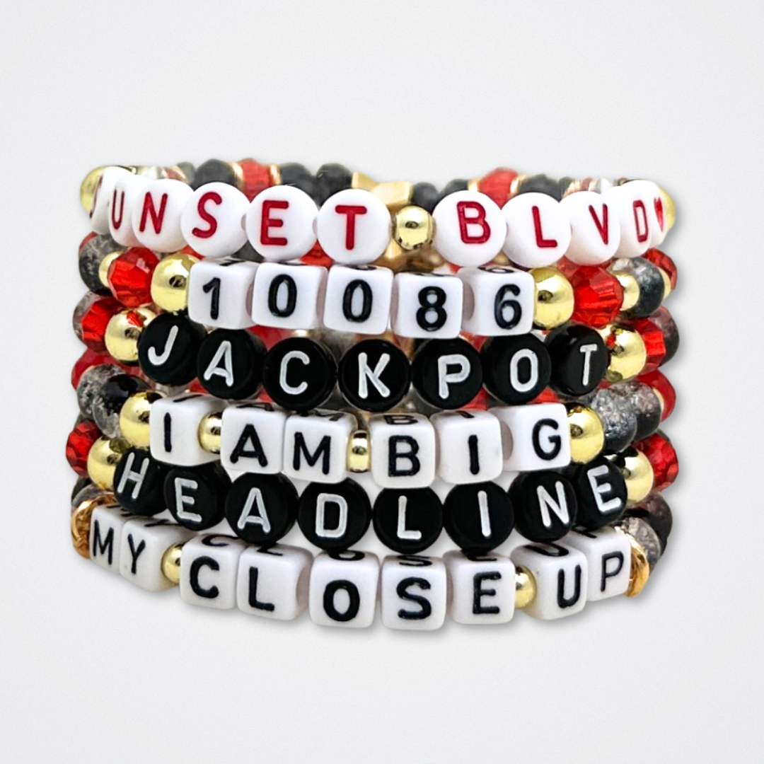 Broadway Stacks CLOSE-UP Collection. 6 stretch bracelets included in Stack. Red, black and gold colored beads. Letter beads that spell quotes. Gold star logo bead to remind you that you shine. Sunset Blvd fans. 
