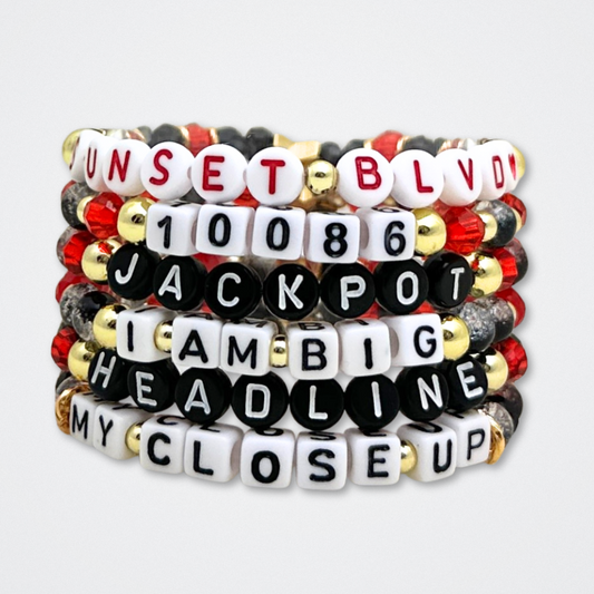 Broadway Stacks CLOSE-UP Collection. 6 stretch bracelets included in Stack. Red, black and gold colored beads. Letter beads that spell quotes. Gold star logo bead to remind you that you shine. Sunset Blvd fans. 