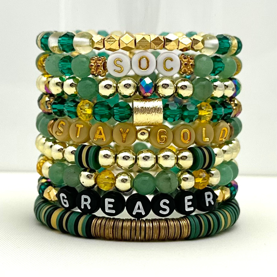 Broadway Stacks STAY GOLD collection. Stretch bracelets included in Stack. Gold, yellow, green and grey colored beads. Letter beads that have show quote or name. Broadway Stacks gold star logo bead on back.