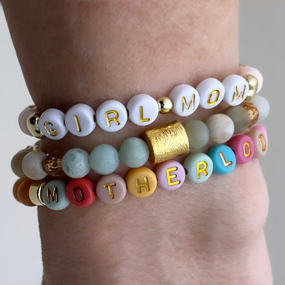 Broadway Stacks Motherlode Special Edition bracelets. Stretch bracelets. Greens, browns, white and gold colored beads. Letter beads that spell Motherlode, Boy Mom, Girl Mom, Twin Mom,