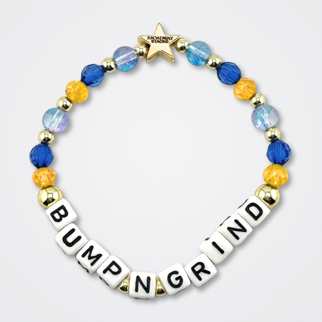 Broadway Stacks CAKE Collection. Bump N Grind bracelet with dark & light blue, yellow and gold colored beads. Letter beads that spell quote from the Coffee Shop. Star logo bead to remind you that you shine. Two Strangers Carry a Cake Across New York fans.