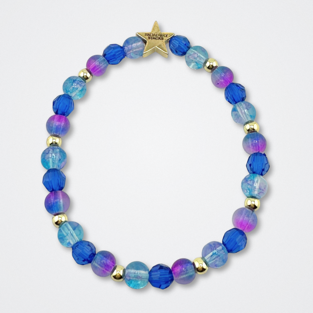 Broadway Stacks CAKE Collection. Bead bracelet with dark and light blue, purple and gold colored beads. Star logo bead to remind you that you shine. Two Strangers Carry a Cake Across New York fans.