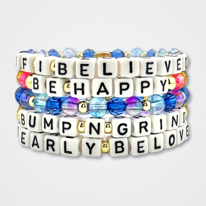 Broadway Stacks CAKE Collection. Five bracelets stacked with letter beads that spell quotes. Blues, purple and gold colored beads. Two Strangers Carry a Cake Across New York fans.