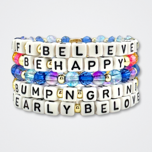 Broadway Stacks CAKE Collection. Five bracelets stacked with letter beads that spell quotes. Blues, purple and gold colored beads. Two Strangers Carry a Cake Across New York fans.