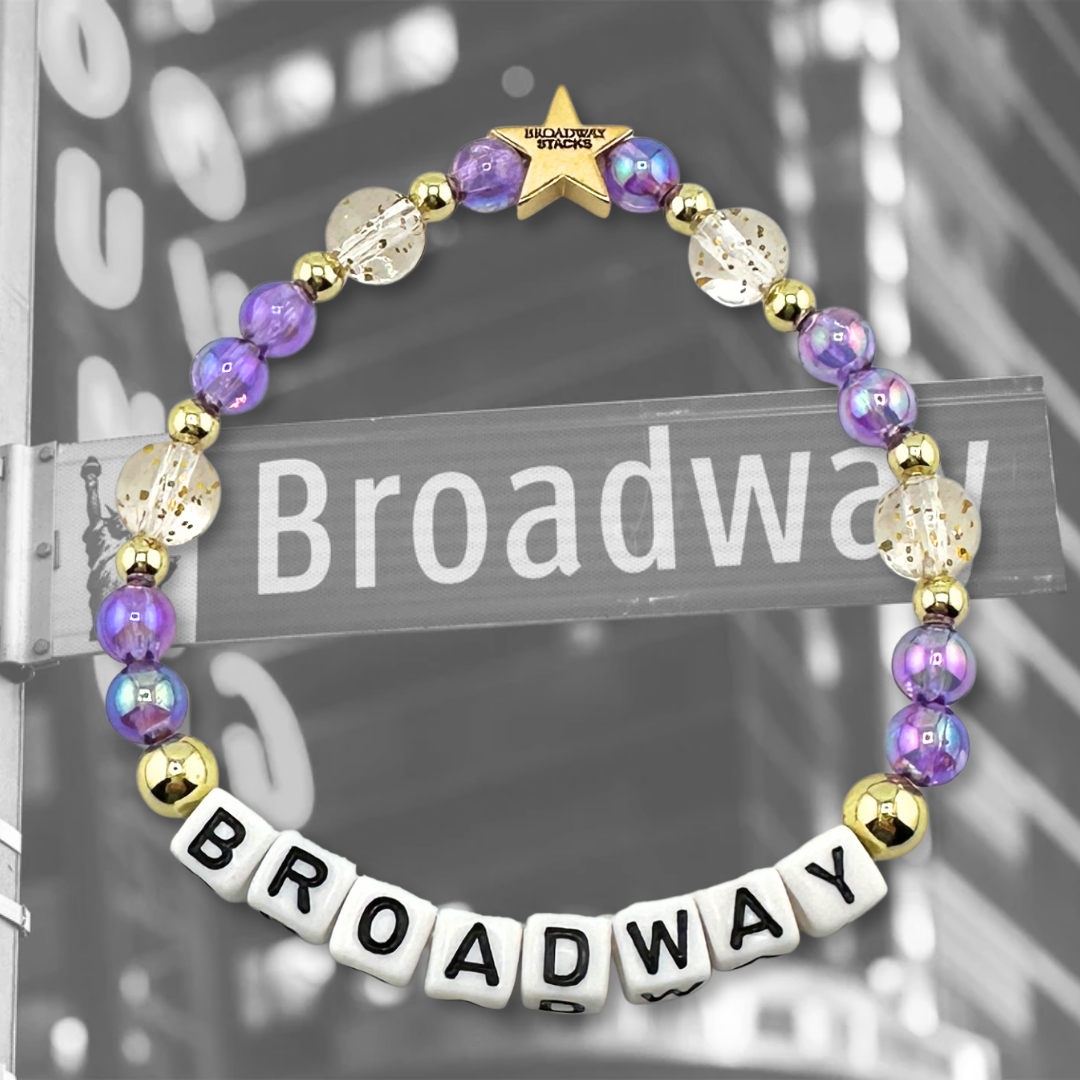 Broadway Stacks BROADWAY bead bracelet displayed on a black/white Broadway sign background. Letter beads spell out quote. Signature star bead to remind you: YOU SHINE! 