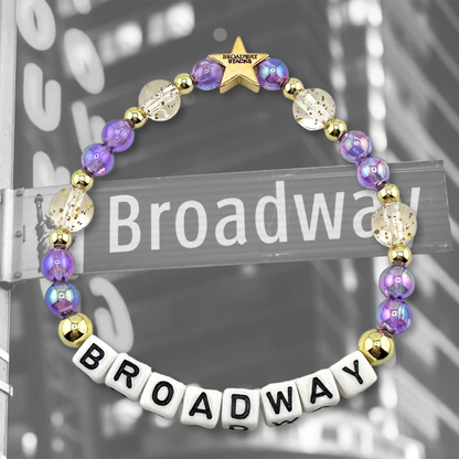 Broadway Stacks BROADWAY bead bracelet displayed on a black/white Broadway sign background. Letter beads spell out quote. Signature star bead to remind you: YOU SHINE! 