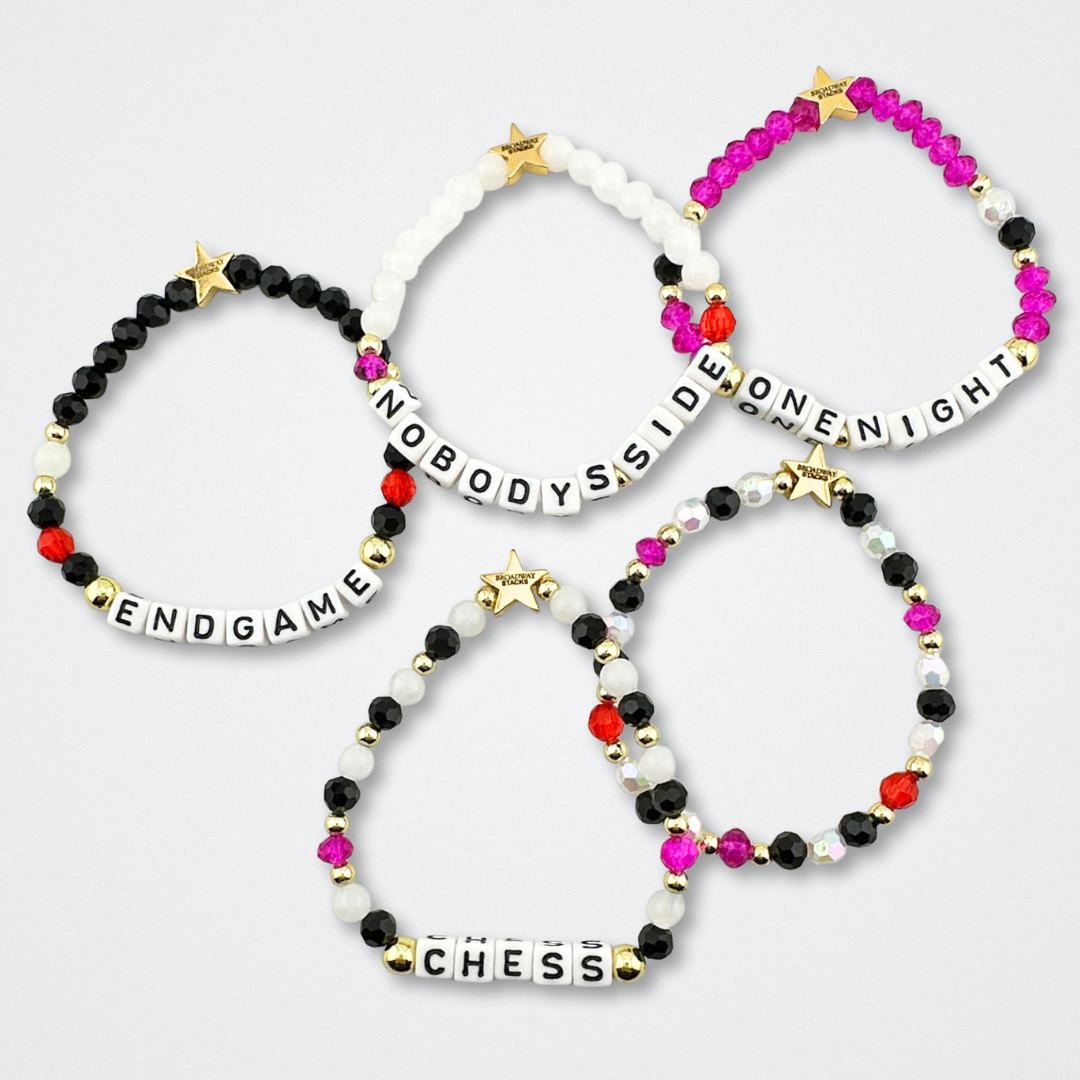 Broadway Stacks CHECKMATE Collection. 5 stretch bracelets included in Stack. Black, white, red, pink and gold colored beads. Letter beads that spell quotes. Star logo bead to remind you that you shine. Chess the Musical fans.