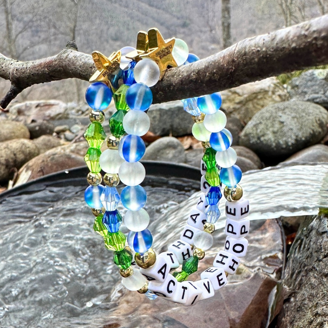 Earth Day Special Edition bracelet. Stack of 3 bracelets. Green, blue, white and gold beads. Letter beads that spell Earth Day 25 and Active Hope. Gold star logo bead to remind you that You Shine.