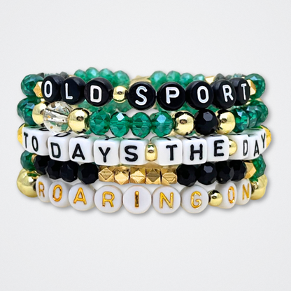 Broadway Stacks NEW MONEY Collection. 5 stretch bracelets included in Stack. Teal, green, black and gold colored beads. Letter beads that spell quotes. Gold star logo bead to remind you that You Shine. Great Gatsby fans.