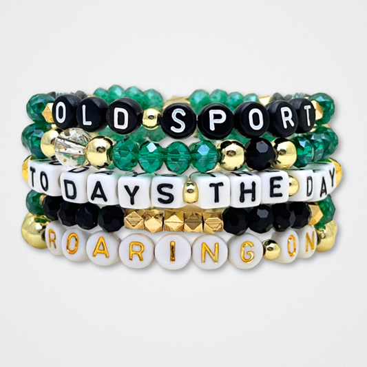 Broadway Stacks NEW MONEY Collection. 5 stretch bracelets included in Stack. Teal, green, black and gold colored beads. Letter beads that spell quotes. Gold star logo bead to remind you that You Shine. Great Gatsby fans.