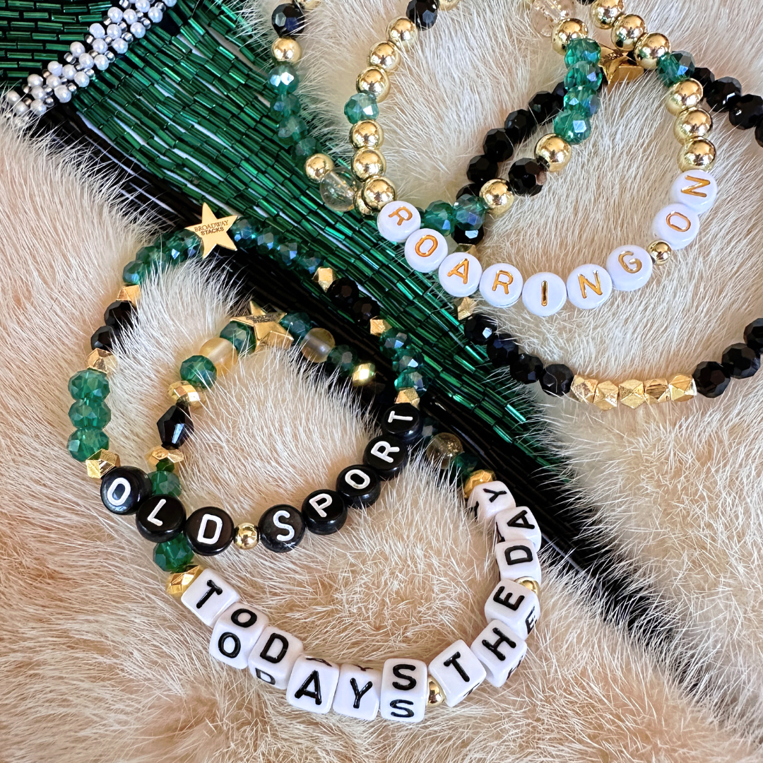 Broadway Stacks NEW MONEY Collection. 5 stretch bracelets included in Stack. Teal, green, black and gold colored beads. Letter beads that spell quotes. Gold star logo bead to remind you that You Shine. Great Gatsby fans.