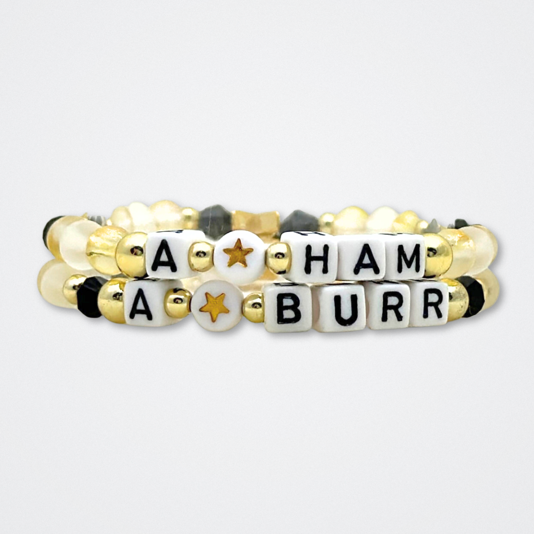 Broadway Stacks REVOLUTION Collection. 5 stretch bracelets included in Stack. Yellow, white, black and gold colored beads. Letter beads that spell quotes. Gold star logo bead to remind you that You Shine. Hamilton the Musical fans. 