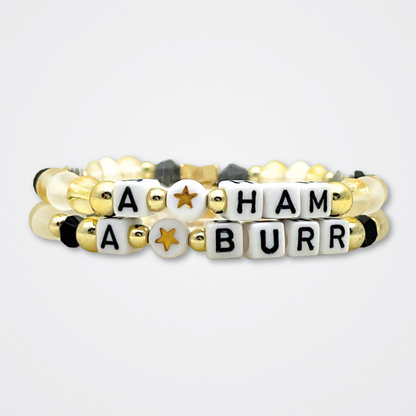 Broadway Stacks REVOLUTION Collection. 5 stretch bracelets included in Stack. Yellow, white, black and gold colored beads. Letter beads that spell quotes. Gold star logo bead to remind you that You Shine. Hamilton the Musical fans. 