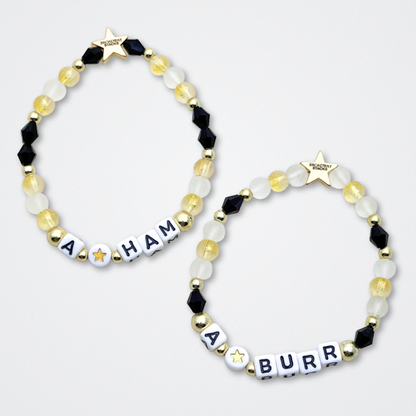 Broadway Stacks REVOLUTION Collection. 5 stretch bracelets included in Stack. Yellow, white, black and gold colored beads. Letter beads that spell quotes. Gold star logo bead to remind you that You Shine. Hamilton the Musical fans. 