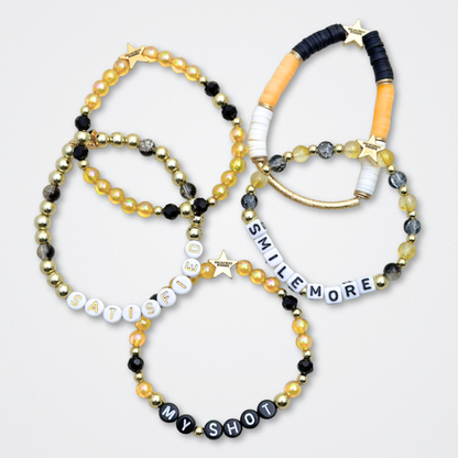 Broadway Stacks REVOLUTION Collection. 5 stretch bracelets included in Stack. Yellow, white, black and gold colored beads. Letter beads that spell quotes. Gold star logo bead to remind you that You Shine. Hamilton the Musical fans. 
