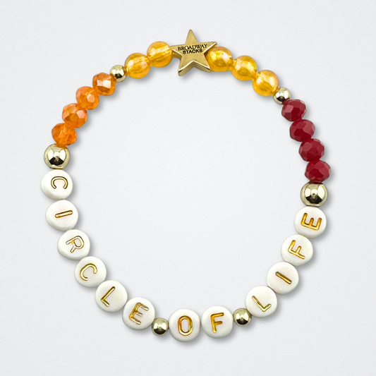 Broadway Stacks SAFARI collection. Red, yellow, orange and gold colored beads on bracelet on gray background. Letter beads that spell quotes. Star logo bead to remind you that YOU SHINE! The Lion King and theatre fans.