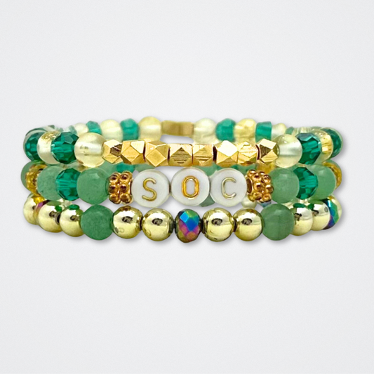 Broadway Stacks STAY GOLD collection. Stretch bracelets included in Stack. Gold, yellow, green and grey colored beads. Letter beads that have show quote or name. Broadway Stacks gold star logo bead to remind you that You Shine. The Outsiders the Musical fans.