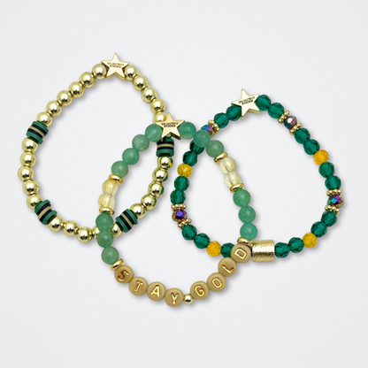 Broadway Stacks STAY GOLD collection. Stretch bracelets included in Stack. Gold, yellow, green and grey colored beads. Letter beads that have show quote or name. Broadway Stacks gold star logo bead to remind you that You Shine. The Outsiders the Musical fans.