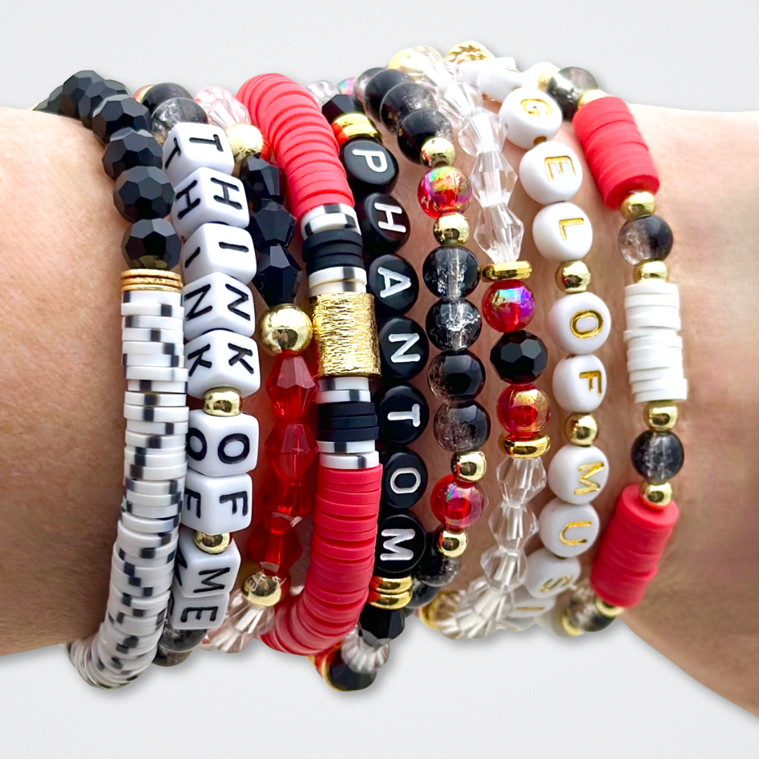 Broadway Stacks MASK collection. Bead bracelets included in Stack. Red, black, white and gold colored beads. Letter beads that spell quotes. Team Phantom, Team Christine, Team Raoul. Gold star logo bead to remind you that You Shine. Phantom of the Opera and Masquerade fans.