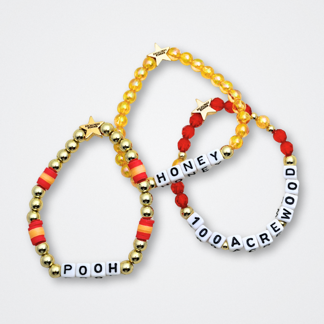 Broadway Stacks HONEY Collection. 3 stretch bracelets included in Stack. Red, yellow and gold colored beads. Letter beads that spell quotes. Gold star logo bead to remind you that You Shine. Winnie the Pooh fans.