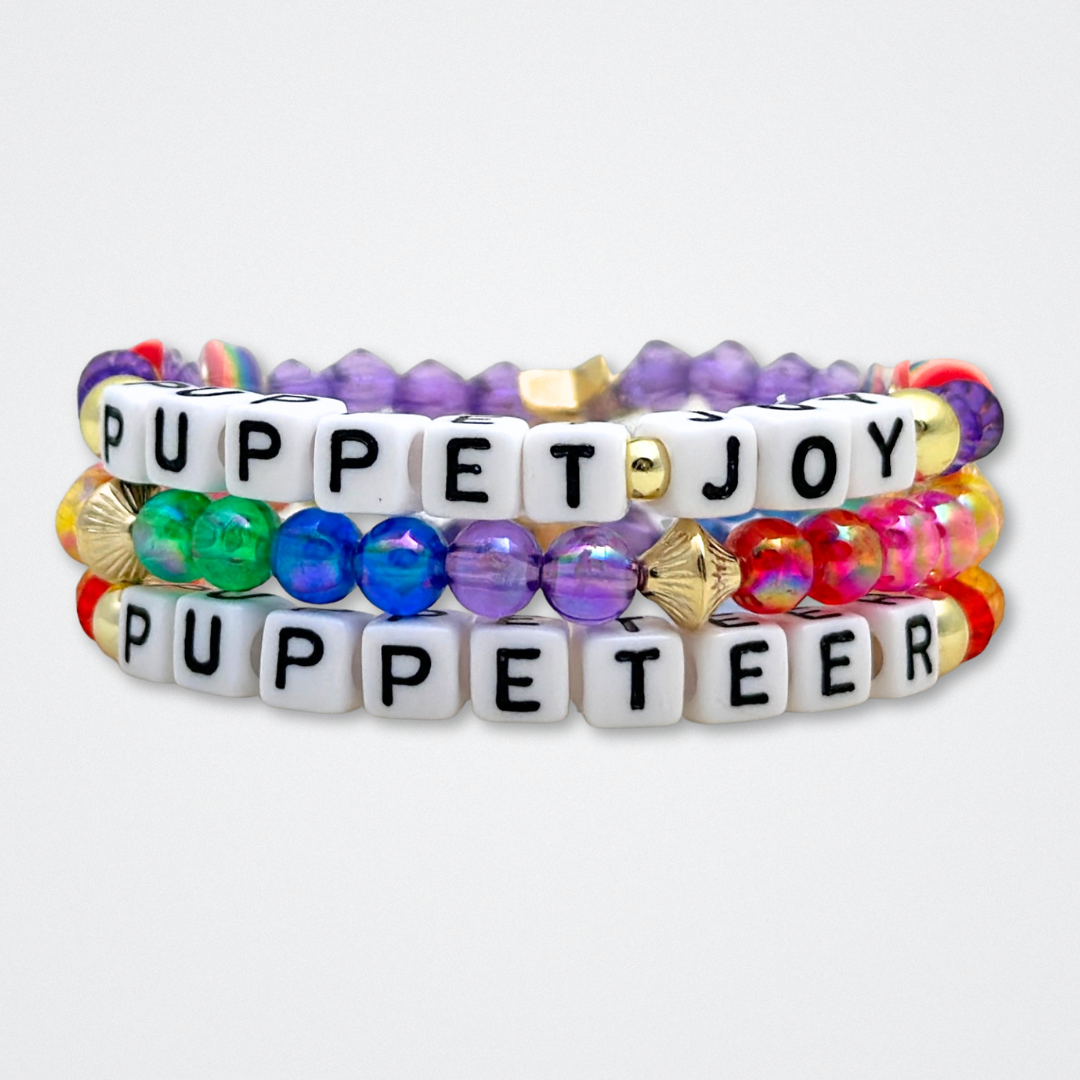 Broadway Stacks PUPPETRY Collection Special Edition bracelet. Stack of 3 bracelets. Rainbow and gold beads. Letter beads that spell Puppeteer and Puppet Joy. Gold star logo bead to remind you that You Shine. 