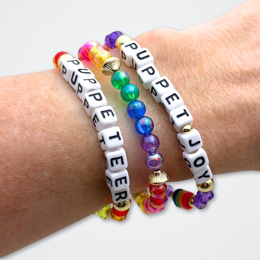 Broadway Stacks PUPPETRY Collection Special Edition bracelet. Stack of 3 bracelets. Rainbow and gold beads. Letter beads that spell Puppeteer and Puppet Joy. Gold star logo bead to remind you that You Shine. 