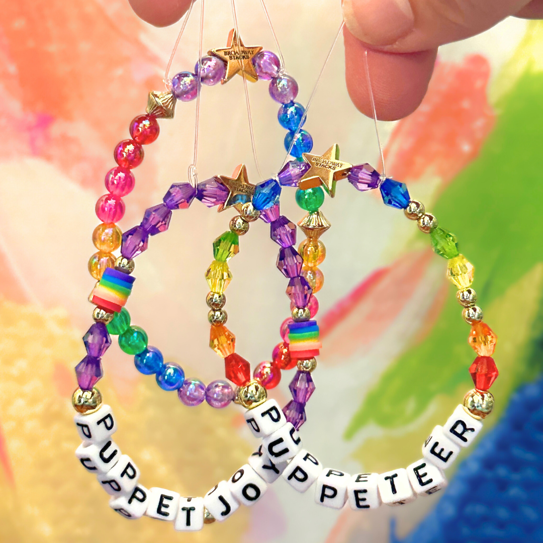 Broadway Stacks PUPPETRY Collection Special Edition bracelet. Stack of 3 bracelets. Rainbow and gold beads. Letter beads that spell Puppeteer and Puppet Joy. Gold star logo bead to remind you that You Shine. 