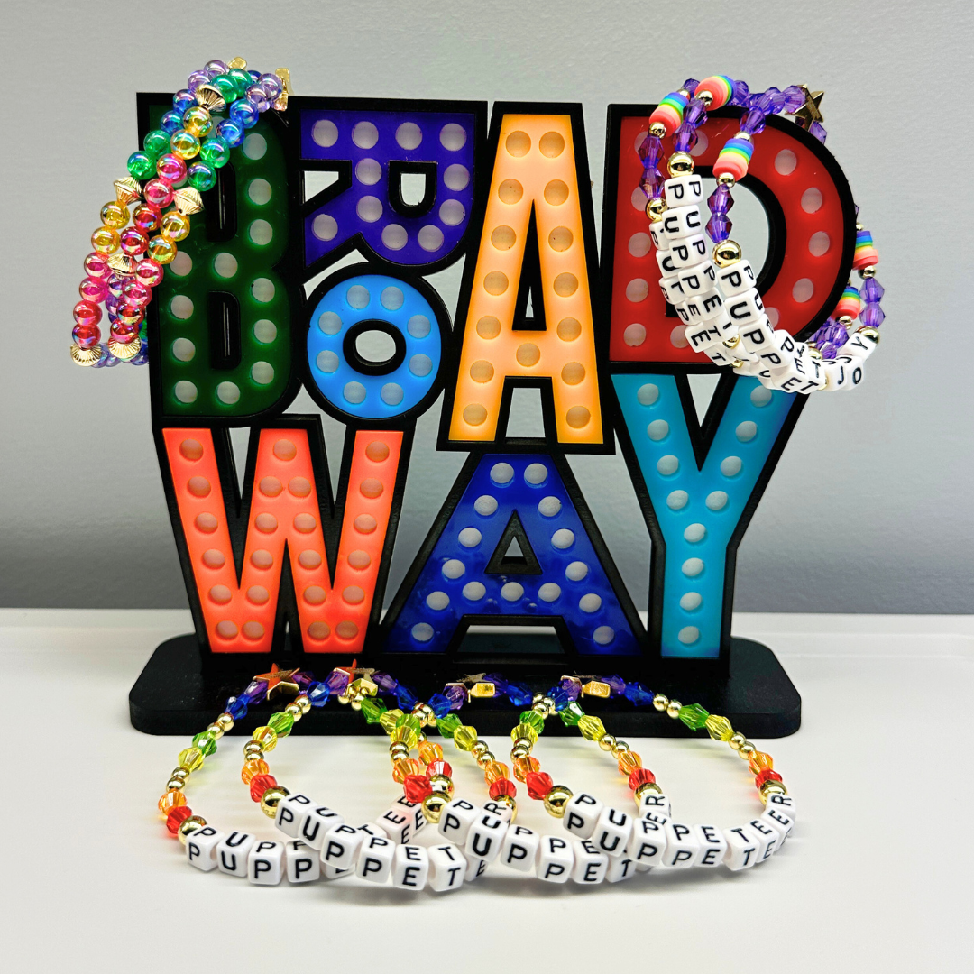 Broadway Stacks PUPPETRY Collection Special Edition bracelet. Stack of 3 bracelets. Rainbow and gold beads. Letter beads that spell Puppeteer and Puppet Joy. Gold star logo bead to remind you that You Shine. 