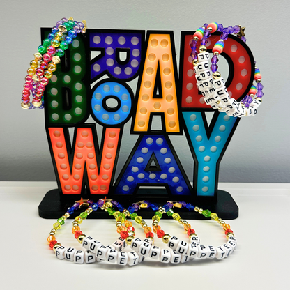 Broadway Stacks PUPPETRY Collection Special Edition bracelet. Stack of 3 bracelets. Rainbow and gold beads. Letter beads that spell Puppeteer and Puppet Joy. Gold star logo bead to remind you that You Shine. 
