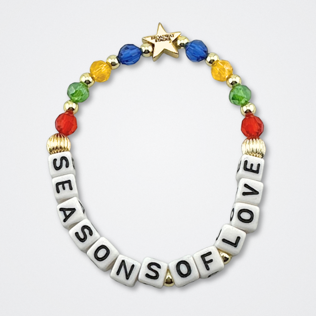 Broadway Stacks theatre-themed bracelet inspired by RENT the Musical. Quote says SEASONS OF LOVE with red, green, yellow and blue beads on a gray background. Signature star bead to remind you that You Shine!