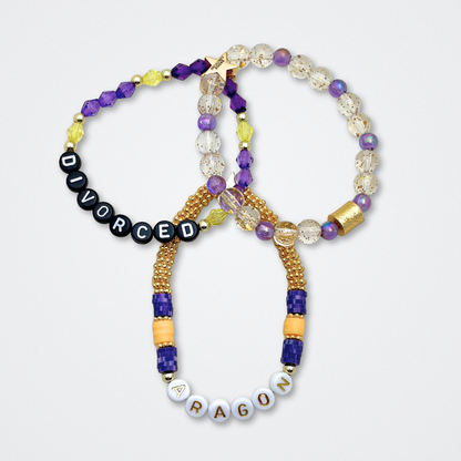 Broadway Stacks QUEEN collection. Stretch bracelets included in Stack. Gold, yellow, green, white, red, pink and blue colored beads. Letter beads that spell each queen. Also Herstory collection. Broadway Stacks gold star logo bead to remind you that You Shine. SIX the Musical fans.