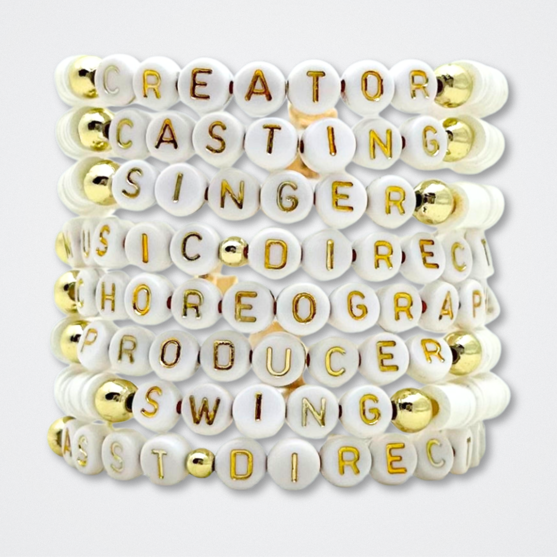 Bracelet with white beads featuring gold letters on a white background. Broadway Stacks theatre-themed Spotlight bracelets highlighting ALL theater roles. Because everyone deserves to shine.