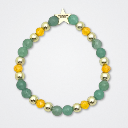 Broadway Stacks STAY GOLD bracelet inspired by The Outsiders Musical. Green, yellow and gold beads. Logo star bead to remind you that YOU SHINE. Displayed on a gray background.