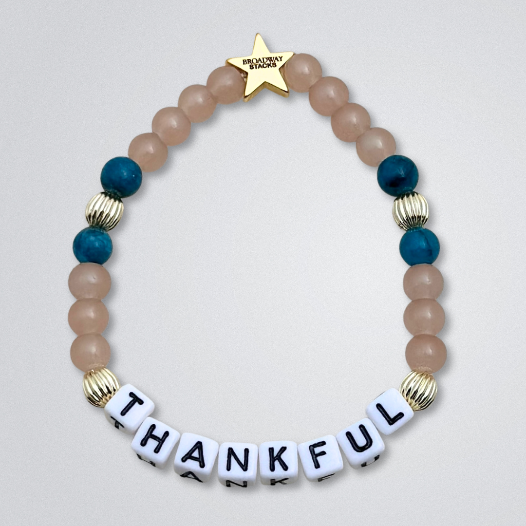 Broadway Stacks SAILOR Collection. 5 stretch bracelets included in Stack. Teal, green, blue and gold colored beads. Letter beads that spell quotes. Swept Away the Musical. Gold star logo bead to remind you that you shine.