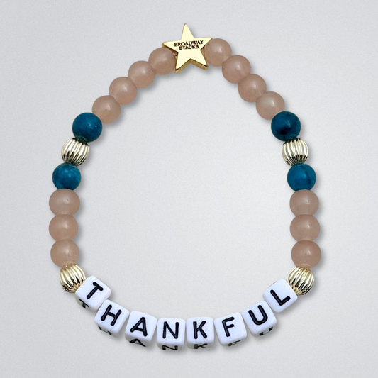 Broadway Stacks SAILOR Collection. 5 stretch bracelets included in Stack. Teal, green, blue and gold colored beads. Letter beads that spell quotes. Swept Away the Musical. Gold star logo bead to remind you that you shine.