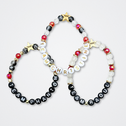 Broadway Stacks MASK collection. Bead bracelets included in Stack. Red, black, white and gold colored beads. Letter beads that spell quotes. Team Phantom, Team Christine, Team Raoul. Gold star logo bead to remind you that You Shine. Phantom of the Opera and Masquerade fans.