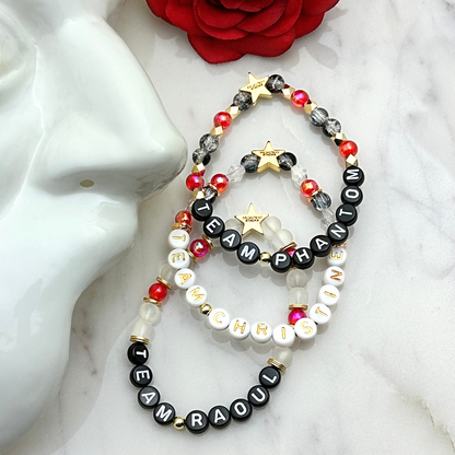 Broadway Stacks MASK collection. Bead bracelets included in Stack. Red, black, white and gold colored beads. Letter beads that spell quotes. Team Phantom, Team Christine, Team Raoul. Gold star logo bead to remind you that You Shine. Phantom of the Opera and Masquerade fans.