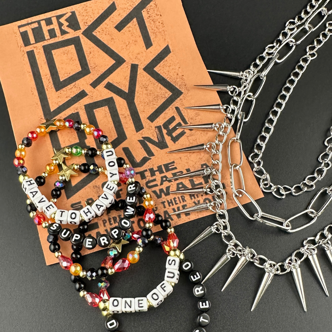 Broadway Stacks VAMPIRE Collection bead bracelets on a The Lost Boys poster background with biker chains. Black, red, orange and gold colored beads with letter beads spelling out quotes. Inspired by The Lost Boys Musical.