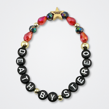 Bead bracelet with letter beads spelling 'DEATH BY STEREO' on a gray background. Broadway Stacks VAMPIRE Collection. Black, red and gold colored beads. Gold star logo bead to remind you that you shine. Inspired by The Lost Boys Musical.