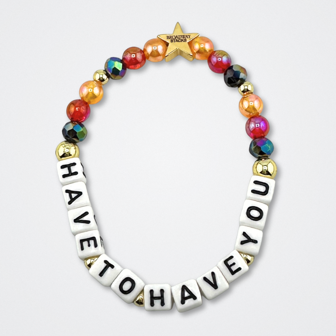 Bead bracelet with letter beads spelling 'HAVE TO HAVE YOU' on a gray background. Broadway Stacks VAMPIRE Collection. Black, red, orange and gold colored beads. Gold star logo bead to remind you that you shine. Inspired by The Lost Boys Musical.