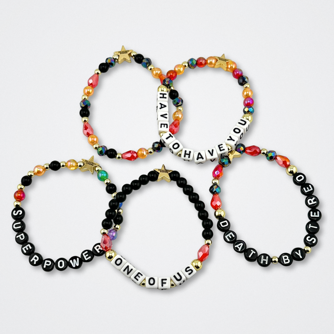 Broadway Stacks VAMPIRE Collection bead bracelets on a gray background. Black, red, orange and gold colored beads with letter beads spelling out quotes. Inspired by The Lost Boys Musical.