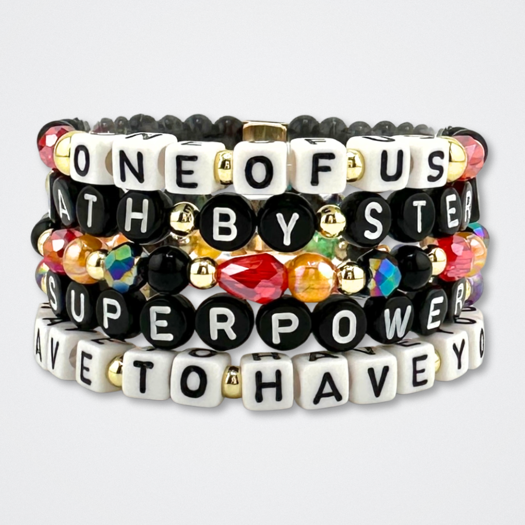 Broadway Stacks VAMPIRE Collection bead bracelets stacked on a gray background. Black, red, orange and gold colored beads with letter beads spelling out quotes. Inspired by The Lost Boys Musical.