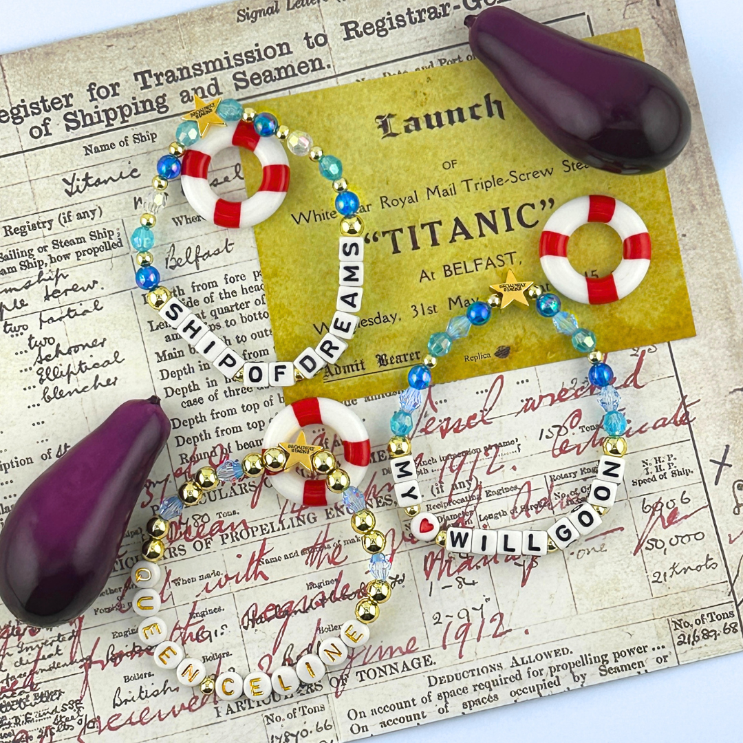 Three bead bracelets with nautical-themed accessories and mini eggplants on a document background. Part of the Broadway Stacks UNSINKABLE Collection. Inspired by Titanique the Musical.
