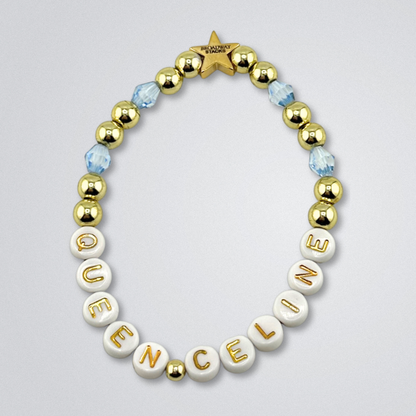Bead bracelet with letter beads spelling 'QUEEN CELINE' on a gray background. Broadway Stacks UNSINKABLE Collection. Blue and gold colored beads. Gold star logo bead to remind you that you shine. Inspired by Titanique the Musical.