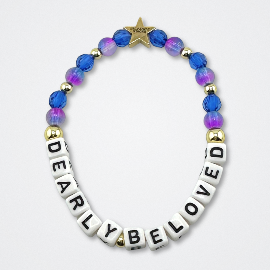 Broadway Stacks CAKE Collection. Dearly Beloved bracelet with blue, purple and gold colored beads. Letter beads that spell quote. Star logo bead to remind you that you shine. Two Strangers Carry a Cake Across New York fans.