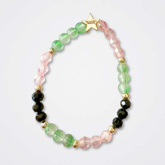 Beaded bracelet on a light gray background. Broadway Stacks WITCH collection. Greens, pinks, black and gold colored beads. Gold star logo bead to remind you that You Shine. 
