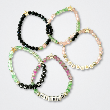 Set of beaded bracelets with word beads on a light gray background. Broadway Stacks WITCH collection. Greens, pinks, black and gold colored beads. Gold star logo bead to remind you that You Shine. 