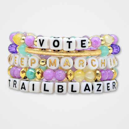 Broadway Stacks CAMPAIGN Collection. 5 stretch bracelets included in Stack. Purple, yellow, teal and gold colored beads. Letter beads that spell quotes. Gold star logo bead to remind you that you shine. Suffs fans. 